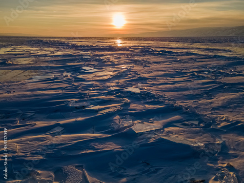 Magnificent sunset over frozen Lake Baikal.  Frozen pieces of ice on the lake surface. Irkutsk region, Russia