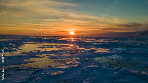 Magnificent sunset over frozen Lake Baikal.   Frozen pieces of ice on the lake surface. Irkutsk region  Russia