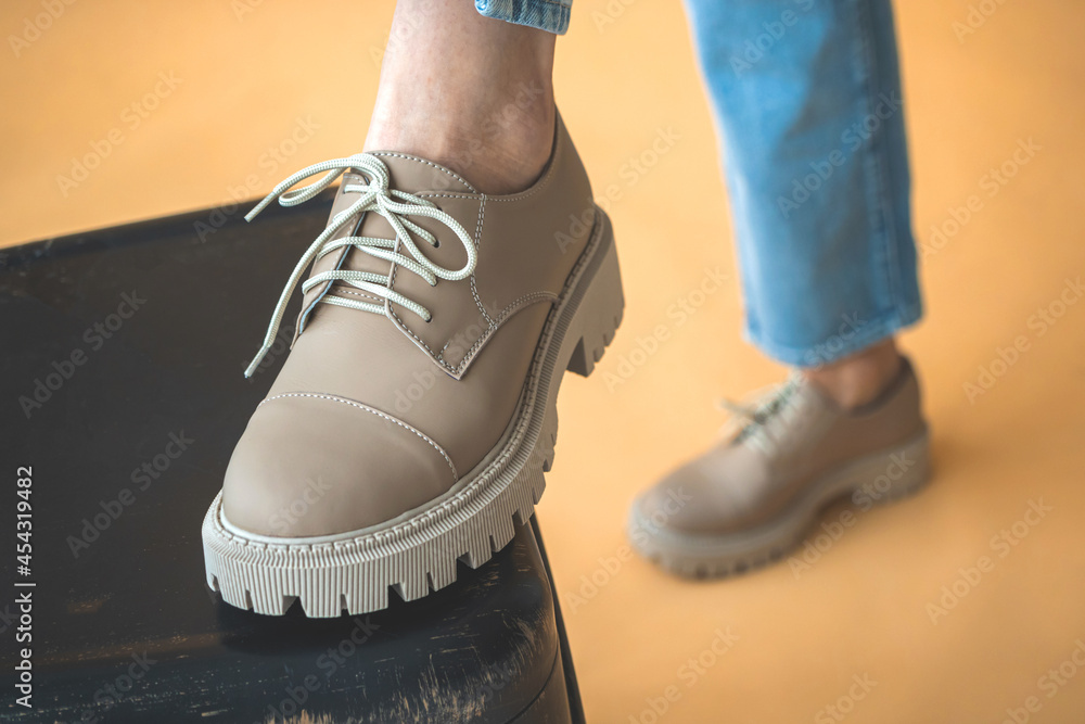 Laces on fashionable sneakers shoes. Women feet in denim clothes. Lifestyle and trendy design background photo