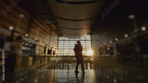 Silhouette of man and a woman meeting in airport terminal after arrival. People hugging. Concept of travel, tourism and transport. Sunset panoramic window at background. 6k downscale 10 bit.