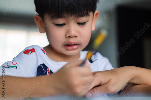 Educate at home. Asian boy make homework  sitting on table where kid is writing. child working on hard homework at home alone.