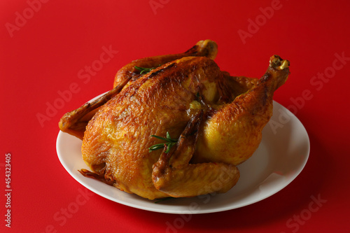 Plate with roast turkey on red background