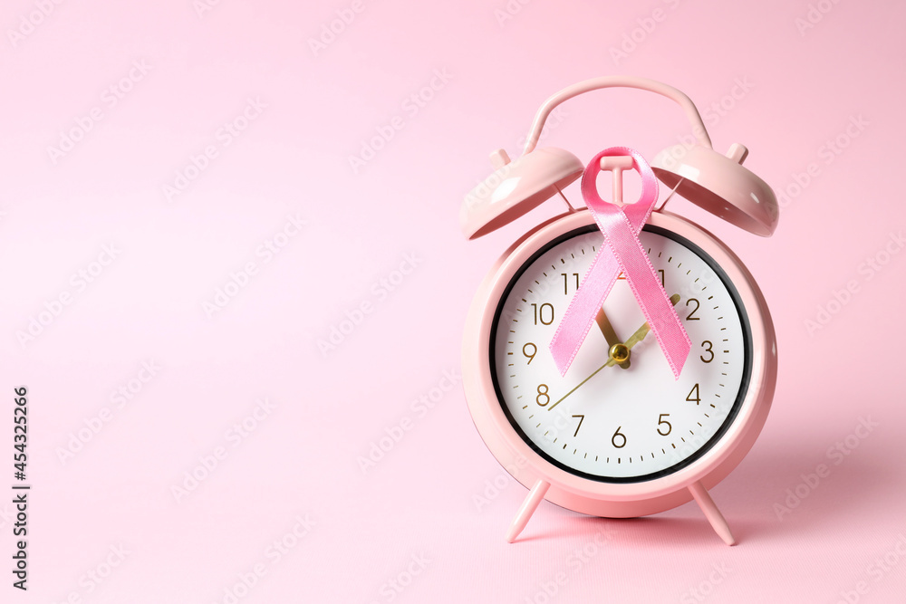 Breast cancer awareness ribbon and alarm clock on pink background - obrazy, fototapety, plakaty 