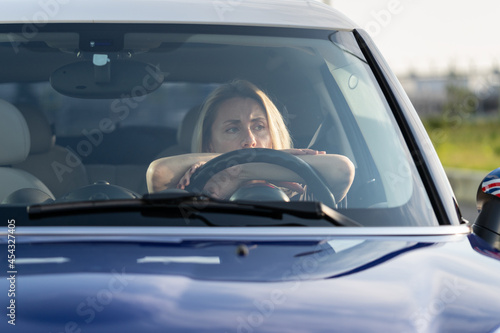 Stressed female sit on driver seat of car not driving look through windshield thinking. Frustrated woman suffering money crisis, troubles at work or relationship breakup pondering inside auto vehicle © DimaBerlin