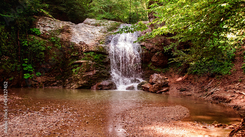 A small waterfall in the forest during the summer.