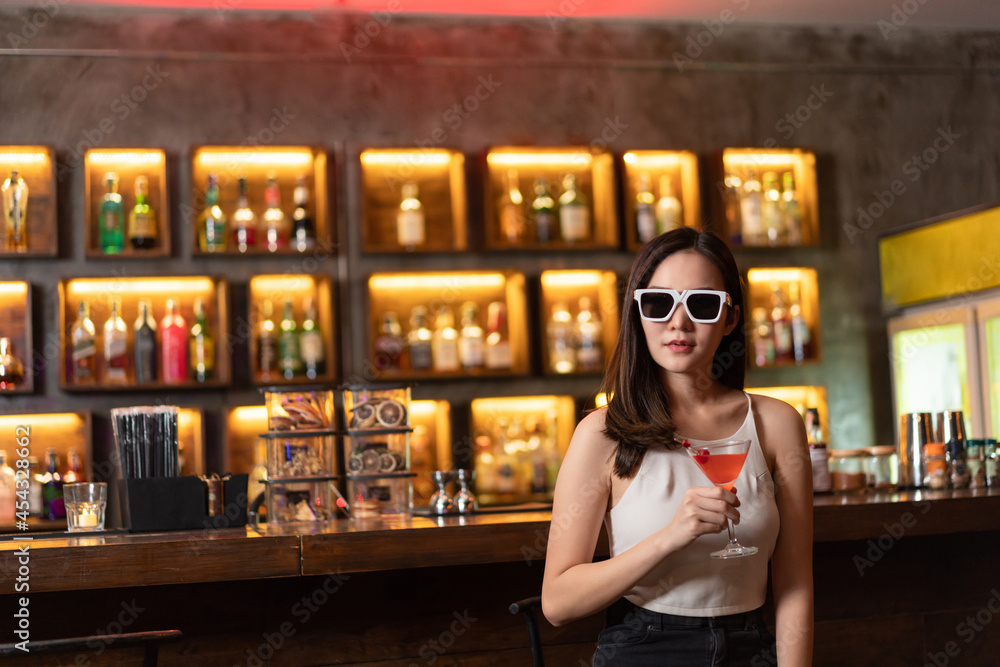 Nightlife concept a sexy girl wearing sunglasses looking mysterious with a straight face holding a drink with cherry on the top