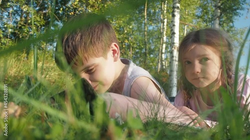 Children reading book on summer nature