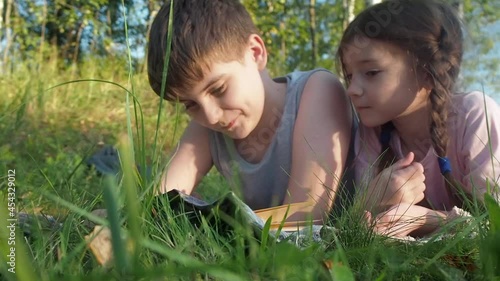 Children reading book on summer nature