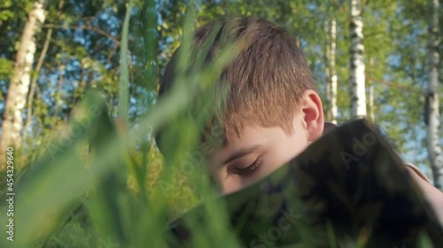 Boy reading book on summer nature