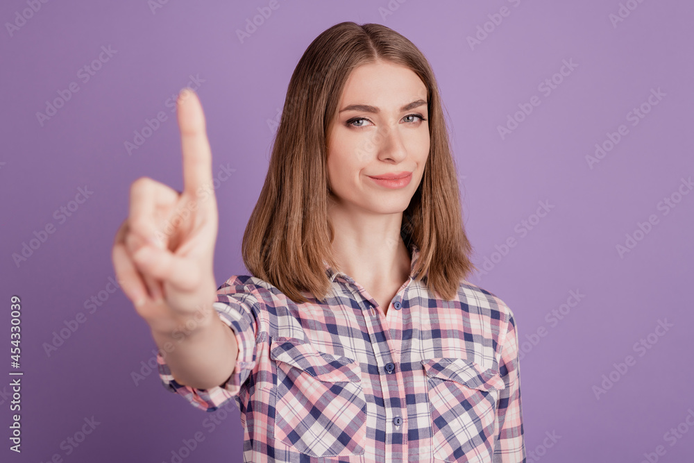 Picture of young woman making stop gesture raising index finger isolated over violet color background