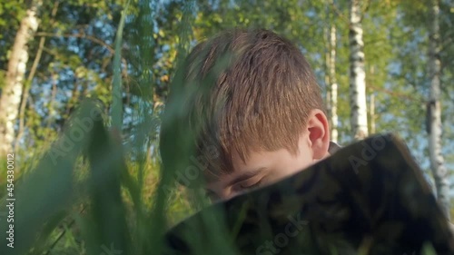 Boy reading book on summer nature