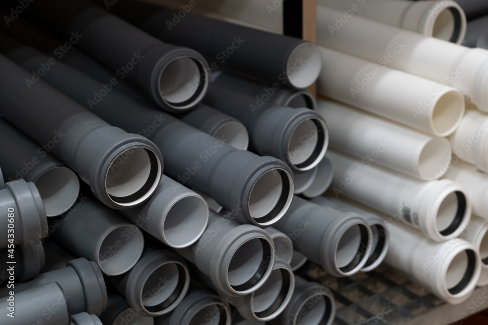 Fototapeta premium Stack of PVC canalization pipes plumbing tube on a hardware store stock. Gray plastic pipes. Industrial for plumber. Construction Materials, selective focus