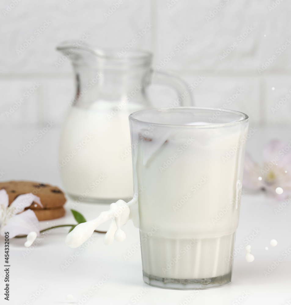 full glass cup of fresh milk with splashes stands on a white table, healthy breakfast full glass cup of fresh milk with splashes stands on a white table, healthy breakfast