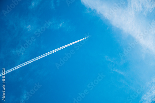 Airplane flying in the blue sky among clouds and sunlight
