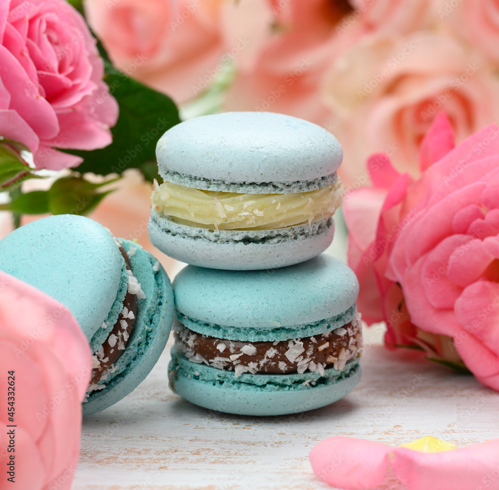 stack of blue macarons on a white table and pink rosebuds, delicious dessert stack of blue macarons on a white table and pink rosebuds, delicious dessert