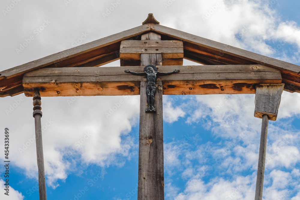 Wooden crucifixion of Jesus Christ on a background of blue sky with clouds. Wooden crucifixion of Jesus Christ on a background of blue sky with clouds.