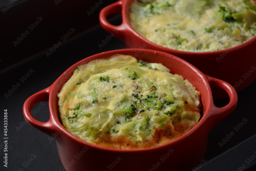 Healthy snack Broccoli  with eggs cheddar cheese and thyme close-up in mini casserole .