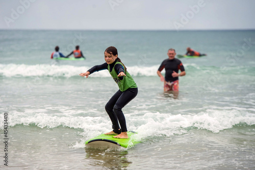 Photography cute young girl learning to surf with her daddy