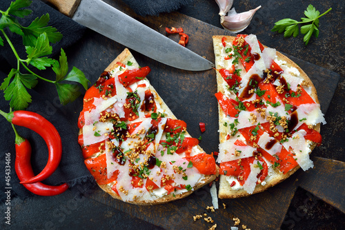 Leckeres vegetarisches XXL-Bruschetta mit gegrilltem Spitzpaprika, Pecorino, Sesam und Frischkäse auf dunklem Untergrund - Spicy Italian bruschetta with grilled peppers, sesame and pecorino   photo