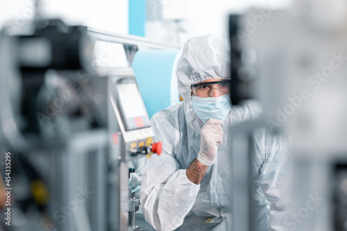 Scientists wearing protective clothing Inspect mask making machines in a laboratory at an industrial plant. Anti-virus production warehouse. concept of safety and prevention coronavirus covid-19.
