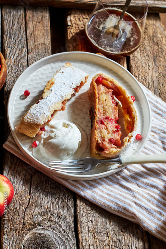 Strudel with apples and cranberries. Icing sugar, coffee, berries. Wooden background, side view.  photo