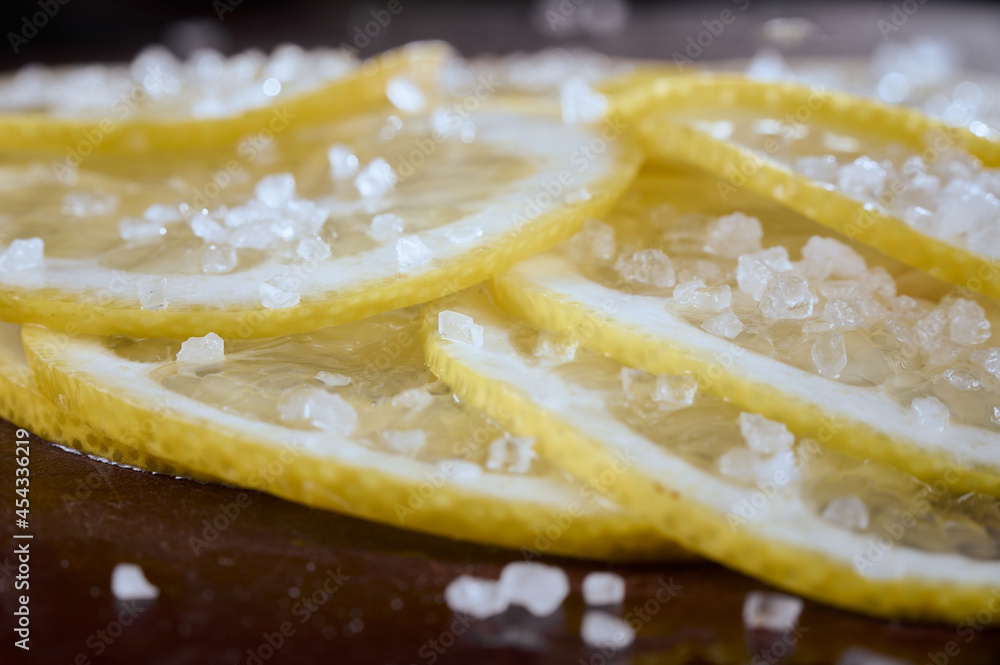 Lemon slices sprinkled with salt close-up on a dark background. Appetizer for cocktails.