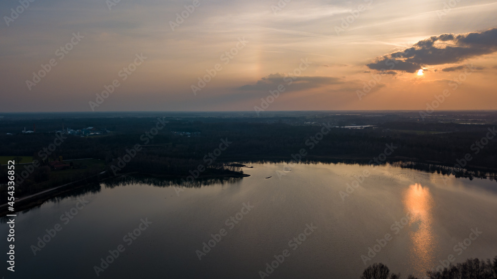 Fototapeta premium Aerial view shot by a drone of a beautiful dramatic and colorful sunset at coast of the lake. Nature landscape. Nature in Europe. reflection, blue sky and yellow sunlight. landscape during sunrise or