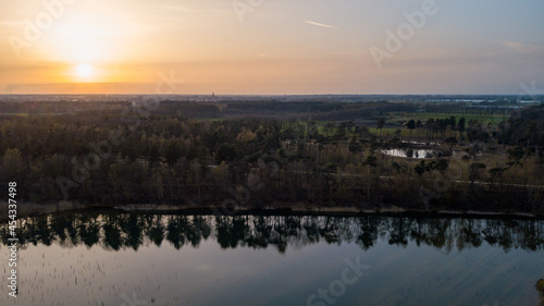 Aerial view shot by a drone of a beautiful dramatic and colorful sunset at coast of the lake. Nature landscape. Nature in Europe. reflection, blue sky and yellow sunlight. landscape during sunrise or