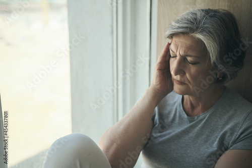 Tableau sur toile Elderly senior woman massaging her temples to reduce her headache