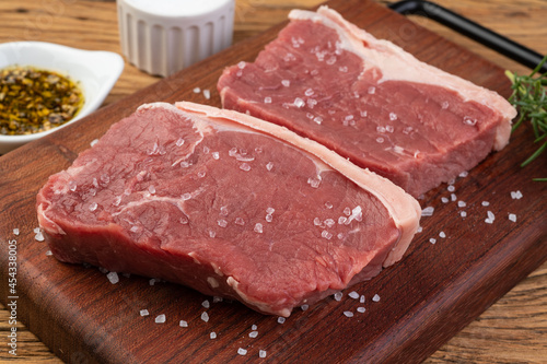 Sliced raw ancho beef, typical argentinian cut, over wooden board with seasonings