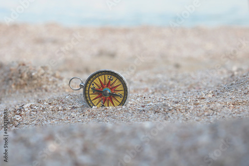Classic navigation compass on beach against blue sea as symbol of tourism with compass, travel with compass and outdoor activities with compass