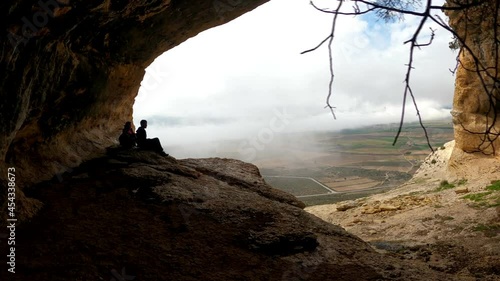 Friends inside cave against landscape. Romantic coupl Scenic rear view of a man and a woman walking in  outstanding caves against beautiful landscape in Cuevas de Zaen, Spain. Europe destinations.  photo