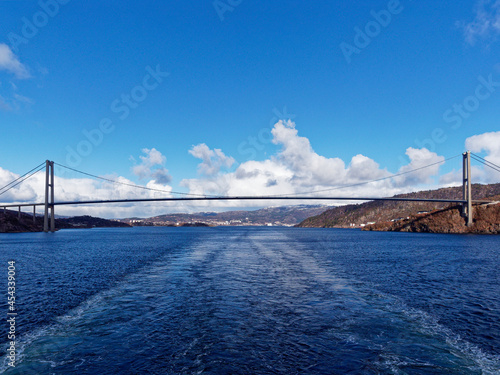 The Full span of the Askoy Suspension Bridge seen from a Vessel departing Bergen Port with its wake centred under the middle of the Bridge. © Julian