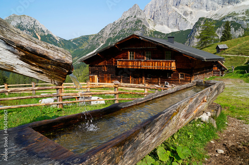 a rustic alpine cabin and a water trough in Neustatt Alm or Neustatt valley by the foot of Dachstein mountain in the Austrian Alps (Styria or Steiermark, Schladming, Austria)