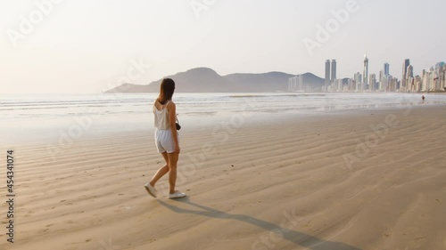Image of tourist woman walking at Balneário Camboriú beach, Brazil.