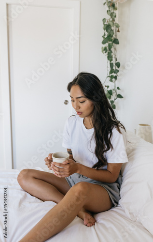 Young adult woman drinking coffee in bed