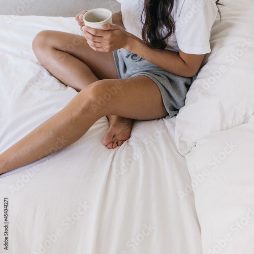 Woman sitting in bed drinking coffee in the morning