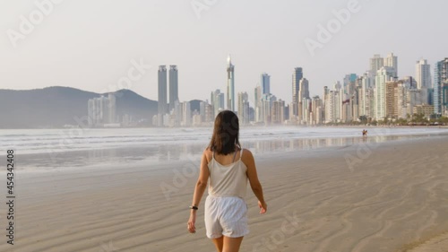 Image of woman walking at the beach early morning, Balneário Camboriú, Brazil.