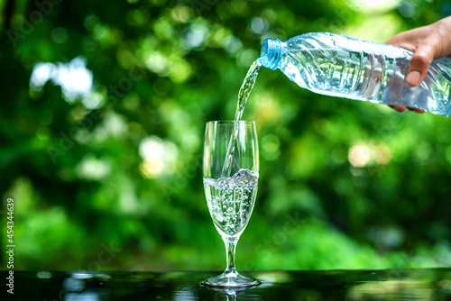 Pouring clean drinking water into the glass located on the bar.