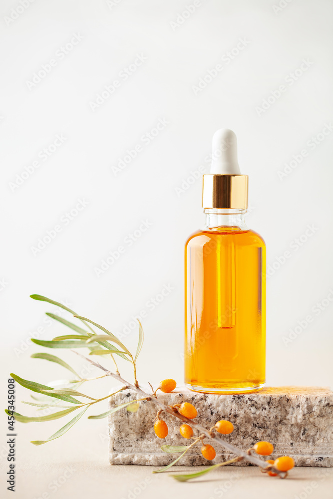Essential oil and branch of sea-buckthorn with berries and leaves on stone podium. Natural cosmetic Essential oil and branch of sea-buckthorn with berries and leaves on stone podium. Natural cosmetic