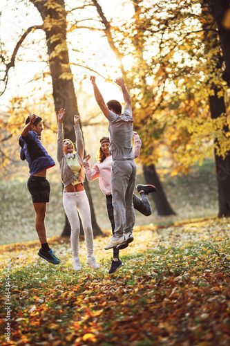 A group of young friends has a great time at the park during a crisp autumn day, surrounded by vibrant foliage and filled with laughter and fun. photo