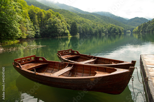 Fototapeta Naklejka Na Ścianę i Meble -  Old wooden boats are on the pier, on a beautiful mountain lake.