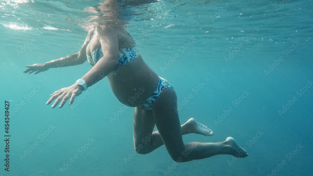 Giovane donna incinta fa ginnastica in gravidanza nell'acqua