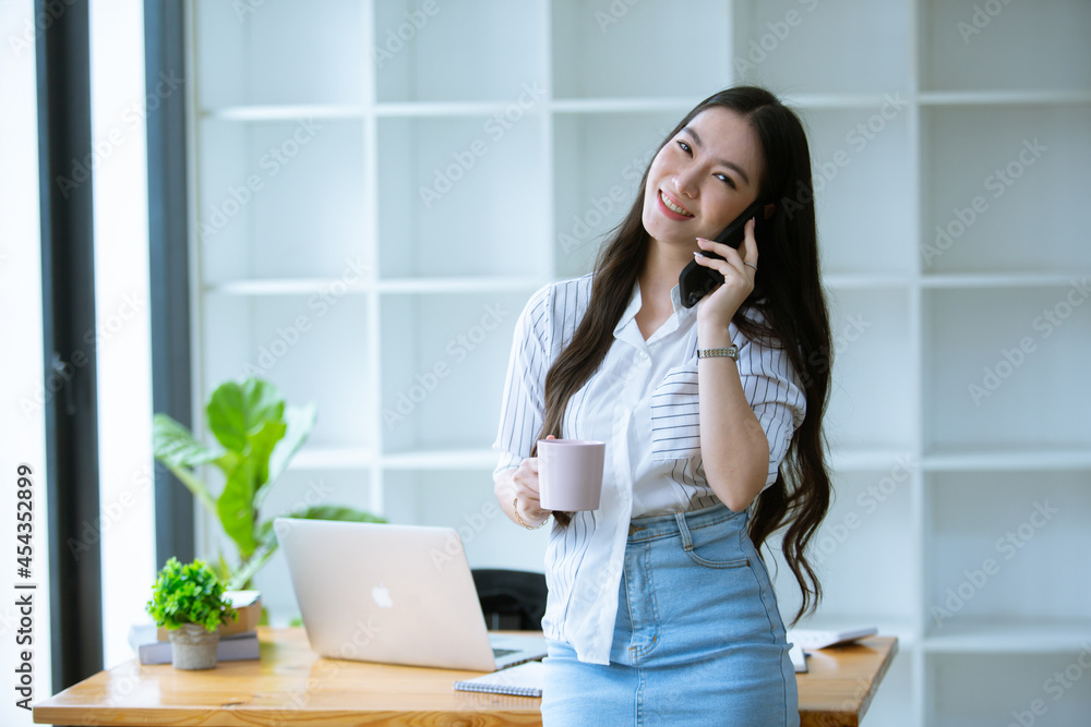 Beautiful Asian woman working freelance working happily Work from home and come up with new projects with her computer, phone and business profit paperwork. Beautiful Asian woman working freelance working happily Work from home and come up with new projects with her computer, phone and business profit paperwork.