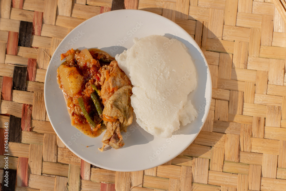Traditional African food dish made from cornmeal porridge and chicken curry stew - obrazy, fototapety, plakaty 