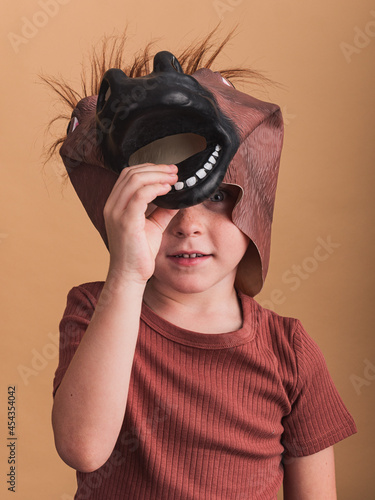 Boy in horse mask on beige background photo