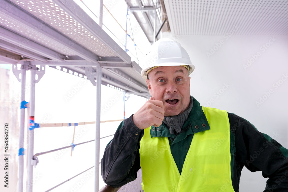 cheerful senior male builder foreman, worker in white hardhat, in work clothes on construction site, crazy worker, concept of repair of buildings, structures cheerful senior male builder foreman, worker in white hardhat, in work clothes on construction site, crazy worker, concept of repair of buildings, structures