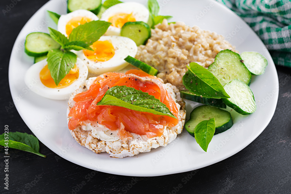 Breakfast oatmeal porridge with boiled eggs, salmon sandwich and cucumbers salad. Healthy food. Lunch. Breakfast oatmeal porridge with boiled eggs, salmon sandwich and cucumbers salad. Healthy food. Lunch.