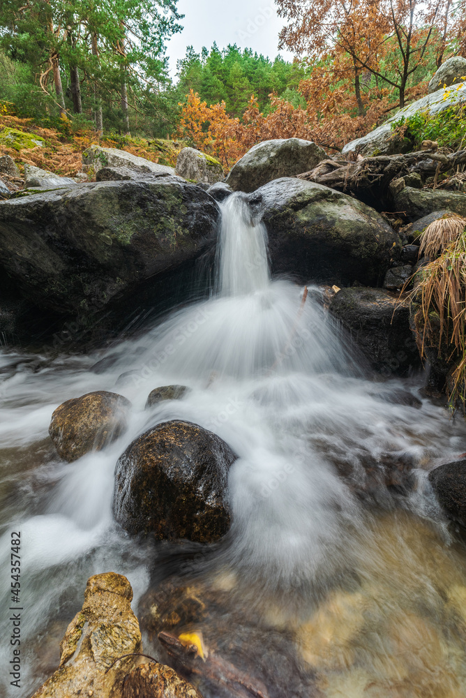 Fast waterfall between boulders and autumn trees Fast waterfall between boulders and autumn trees