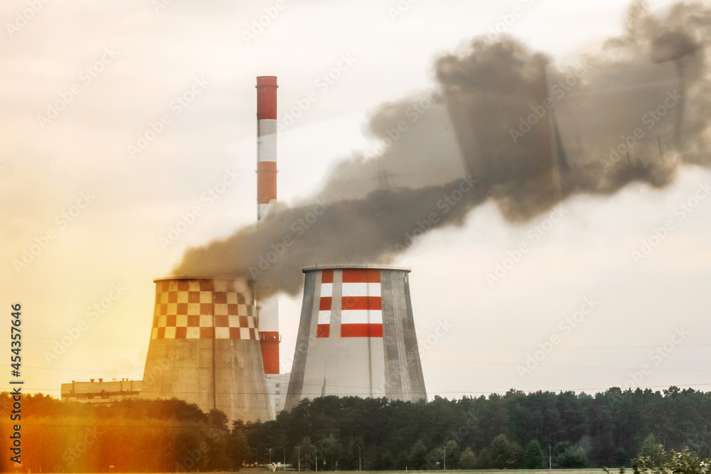 Dirty production. Gray smoke is emitted from the cooling tower near the chimney of an industrial enterprise Dirty production. Gray smoke is emitted from the cooling tower near the chimney of an industrial enterprise